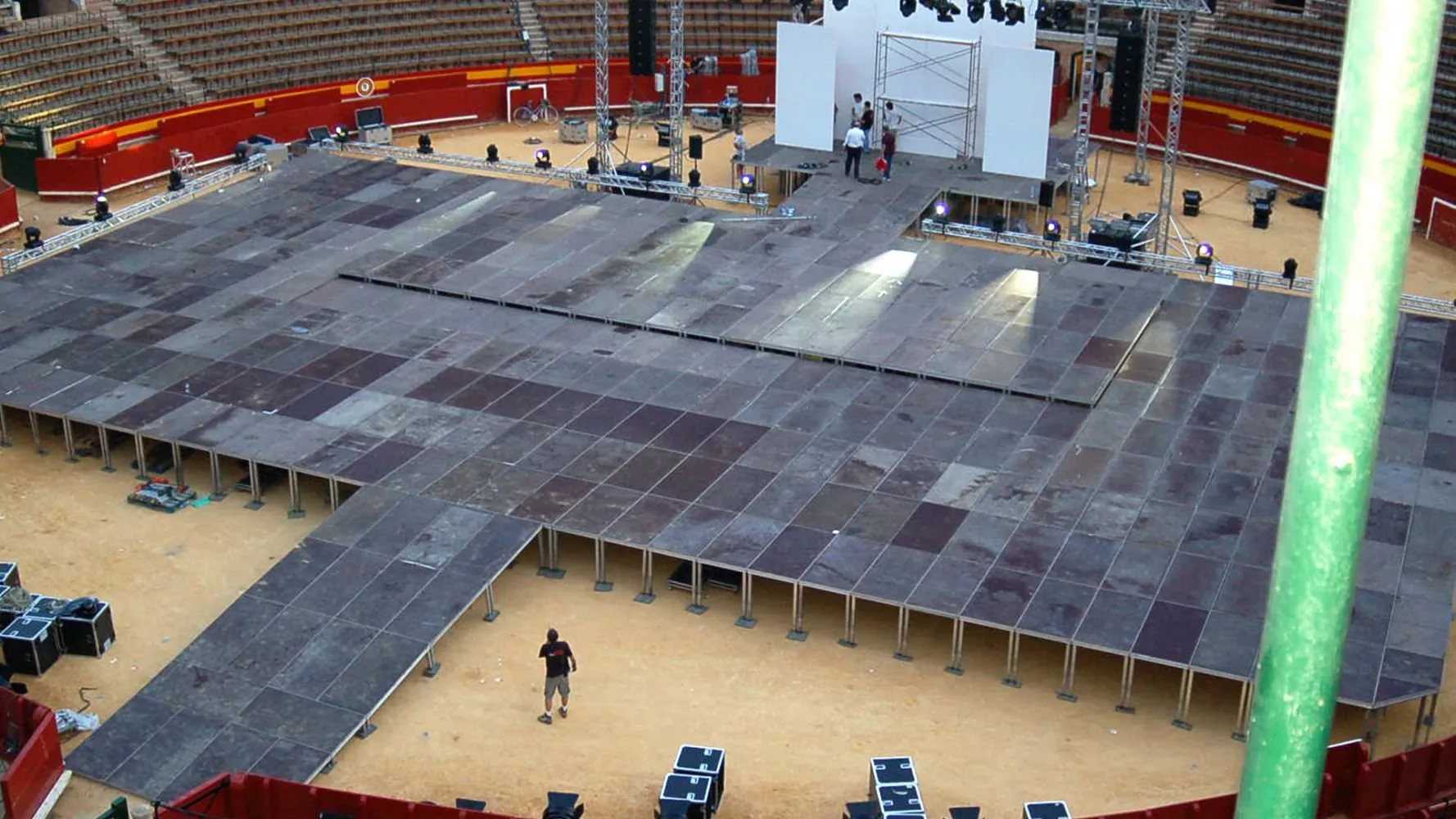 Stage platforms laid out across an arena floor, with a set under construction